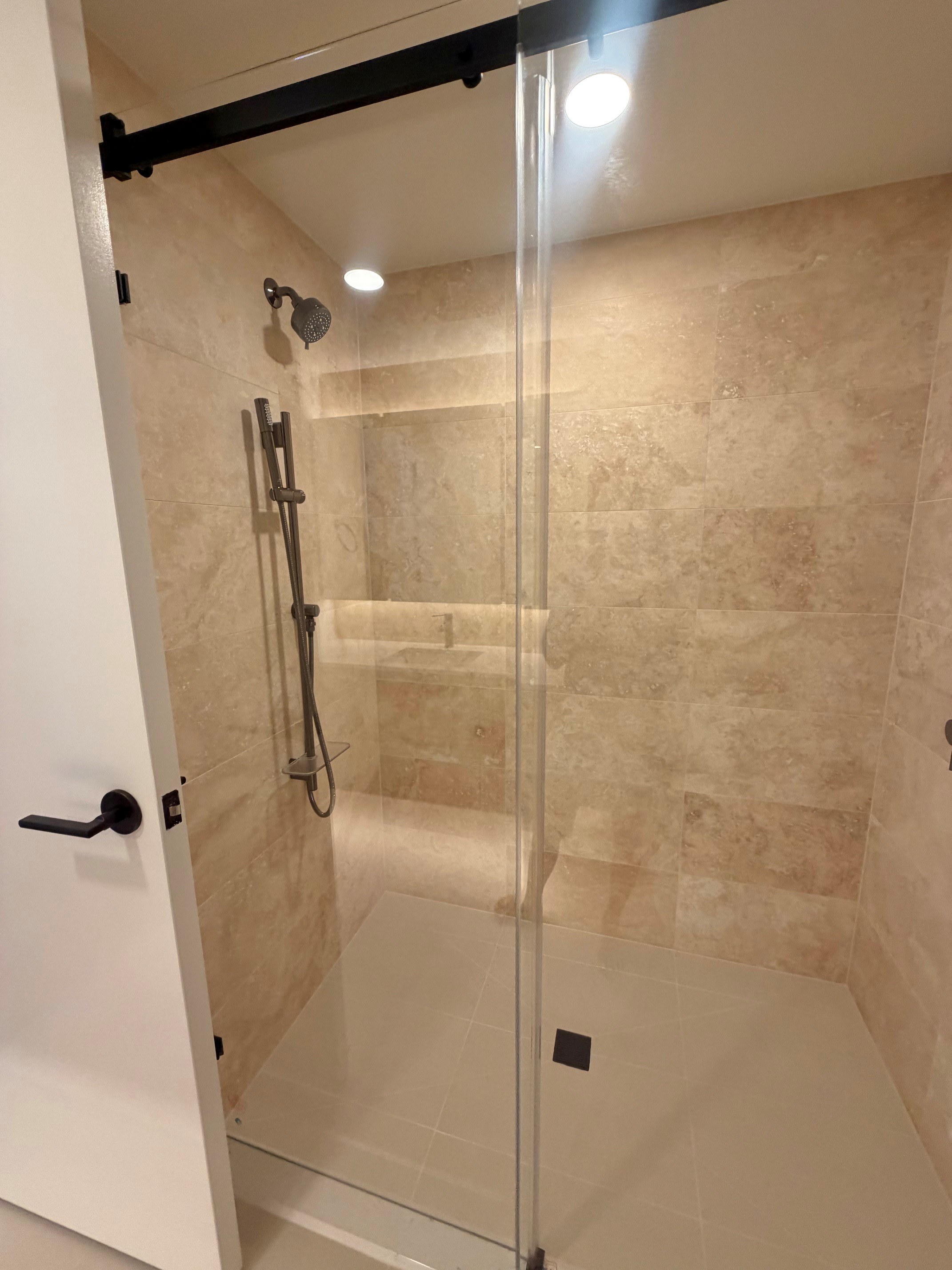 A bathroom with a walk-in shower and a glass door.